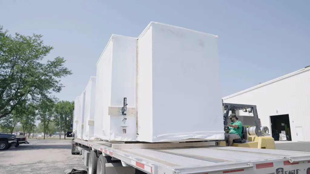 Worker using a forklift to place pods on a flat bed for delivery