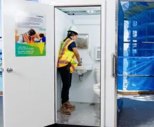 Woman worker on active construction site washing their hands in an H³ Wellness Pod