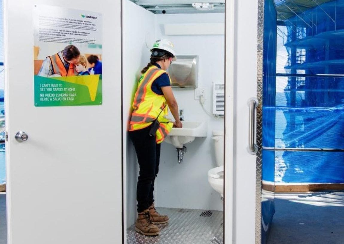 Woman worker on active construction site washing their hands in an H³ Wellness Pod