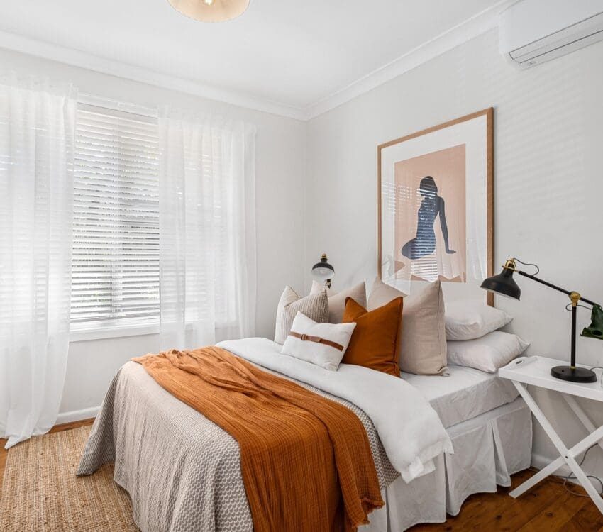 Workforce housing bedroom with queen sized bed covered in blankets and pillows